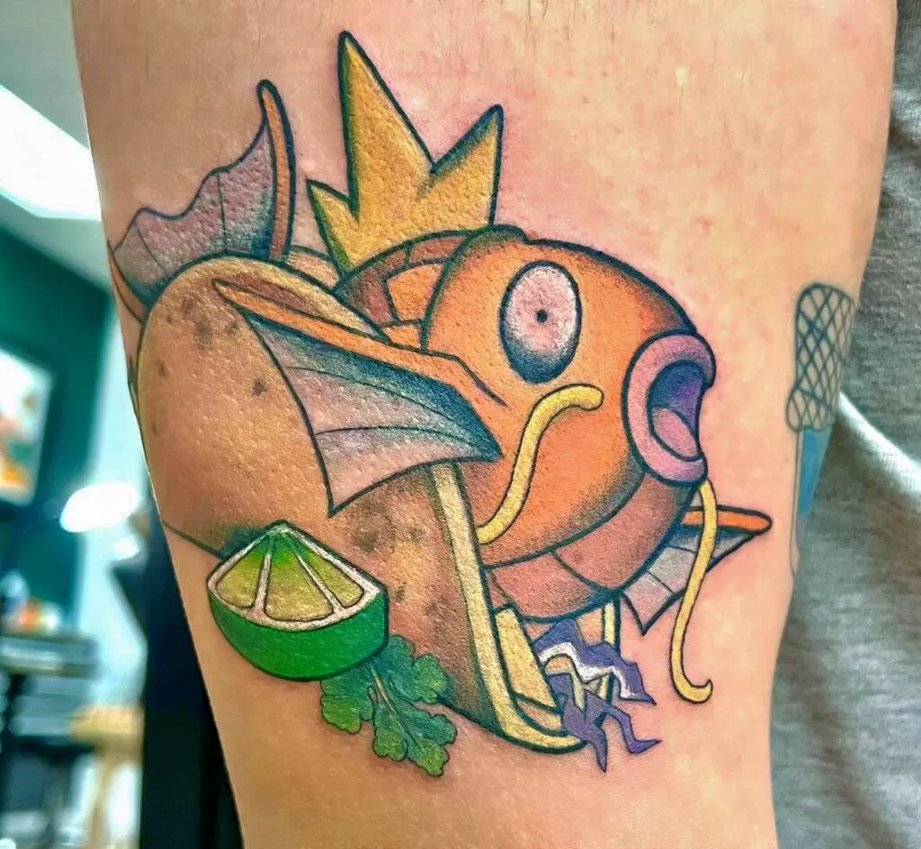 A color tattoo of a stylized fish resembling Magikarp with taco elements, including a tortilla, lime, and cilantro, on someone's leg.